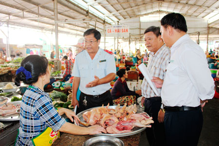 Đoàn Thanh, kiểm tra an toàn vệ sinh thực phẩm thành phố đang kiểm tra một sạp kinh doanh thịt gia cầm tại chợ An Thới.
