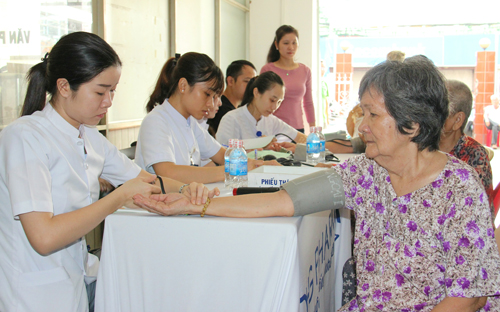 Thành viên Đội thầy thuốc tình nguyện đang đo huyết áp cho người cao tuổi.