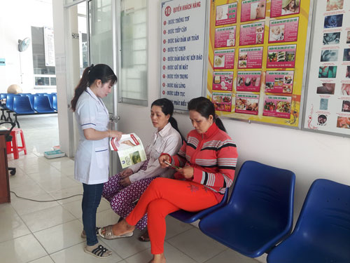 Bà Lê Thị Ánh Nguyệt, Phó Trạm Y tế phường Bùi Hữu Nghĩa phát tờ rơi cho chị em tới thực hiện KHHGĐ tại trạm