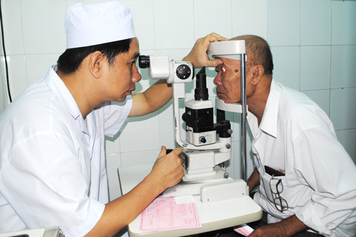 BS.CKII Mai Hoàng Trí đang khám bệnh bằng máy sinh hiển vi cho bệnh nhân võng mạc tiểu đường tại bệnh viện.