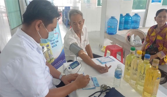 Bà con đến khám bệnh được nhân viên y tế kiểm tra huyết áp